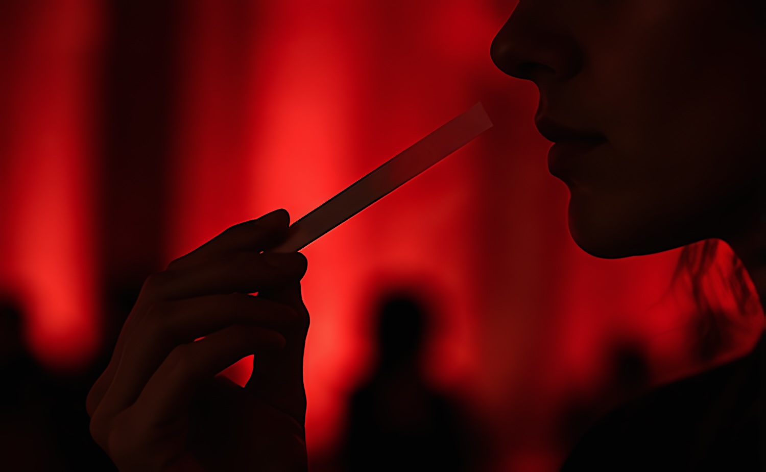 Une silhouette sentant une mouillette dans une lumière rouge